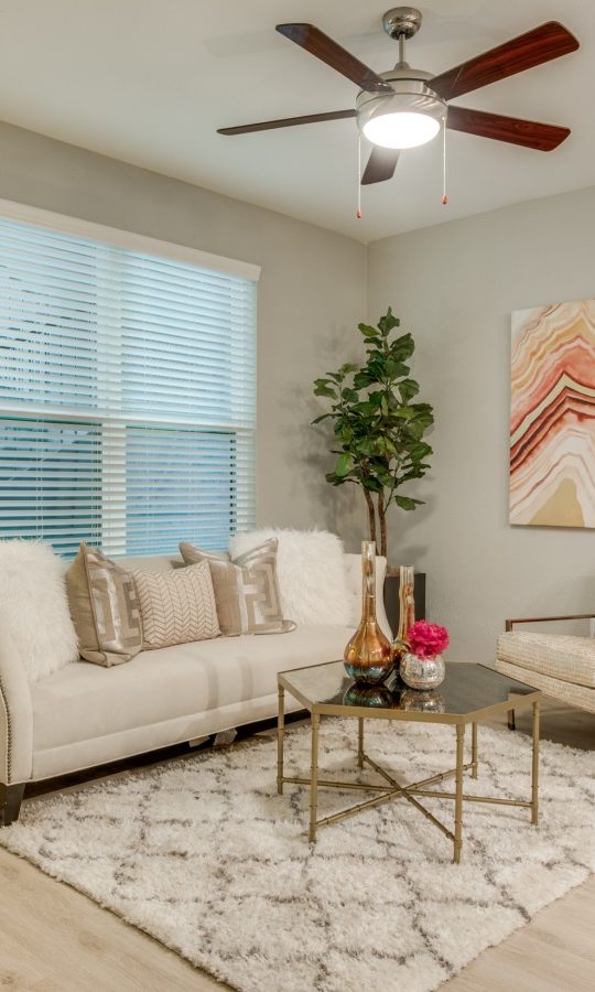 a living room with a ceiling fan and white walls at The  Sophia